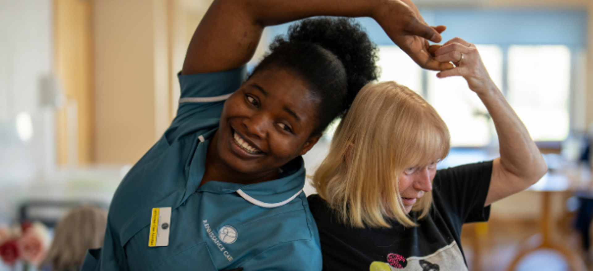 Staff member and resident share a joyful dance, twirling each other around.