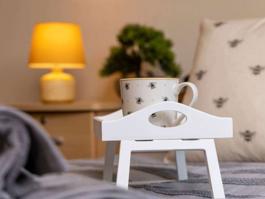 Breakfast tray with mug on bed, cosy scene with lamp and plants