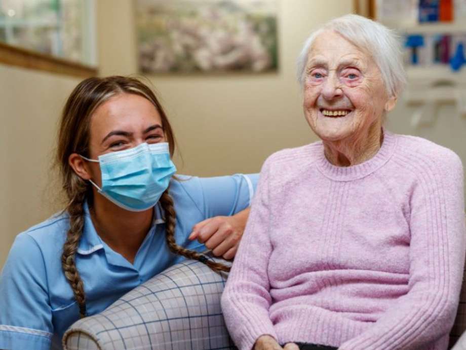 A staff member and resident are looking towards a camera and smiling