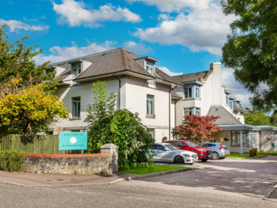 Riverside Care Home Exterior in Aberdeen. A large white building with a car park at the entrance.