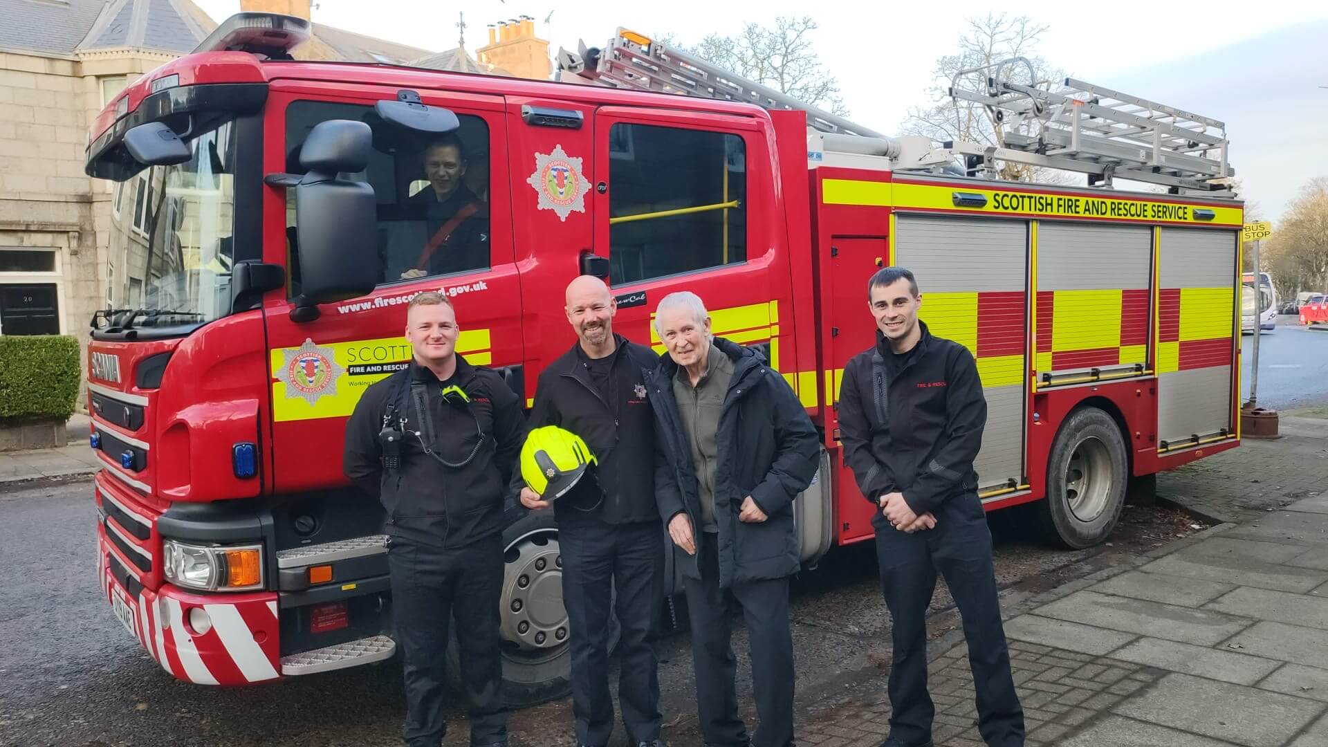 A care home resident stands surrounded by firefighters and a fire engine as he reminisces about his past career in the service