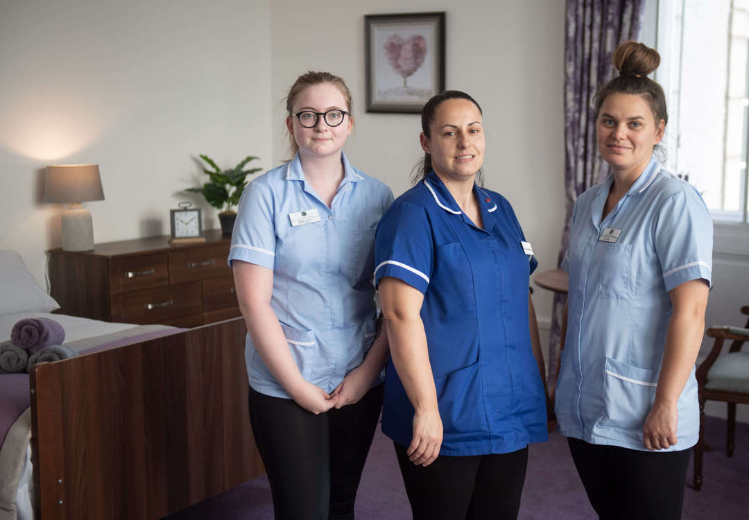 three staff members stand in one of the care homes bedrooms