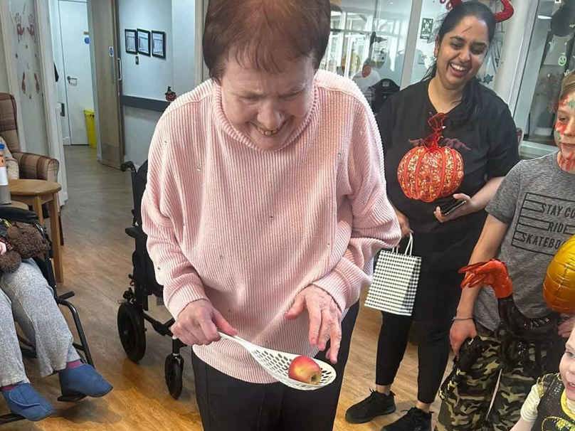 A care home resident enjoys a traditional Halloween game of 'dooking for apples'