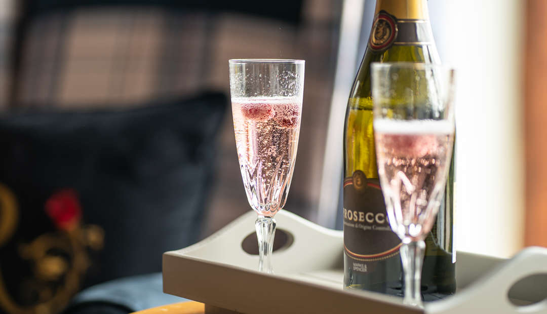 close up of two glasses of prosecco and a bottle resting on a table