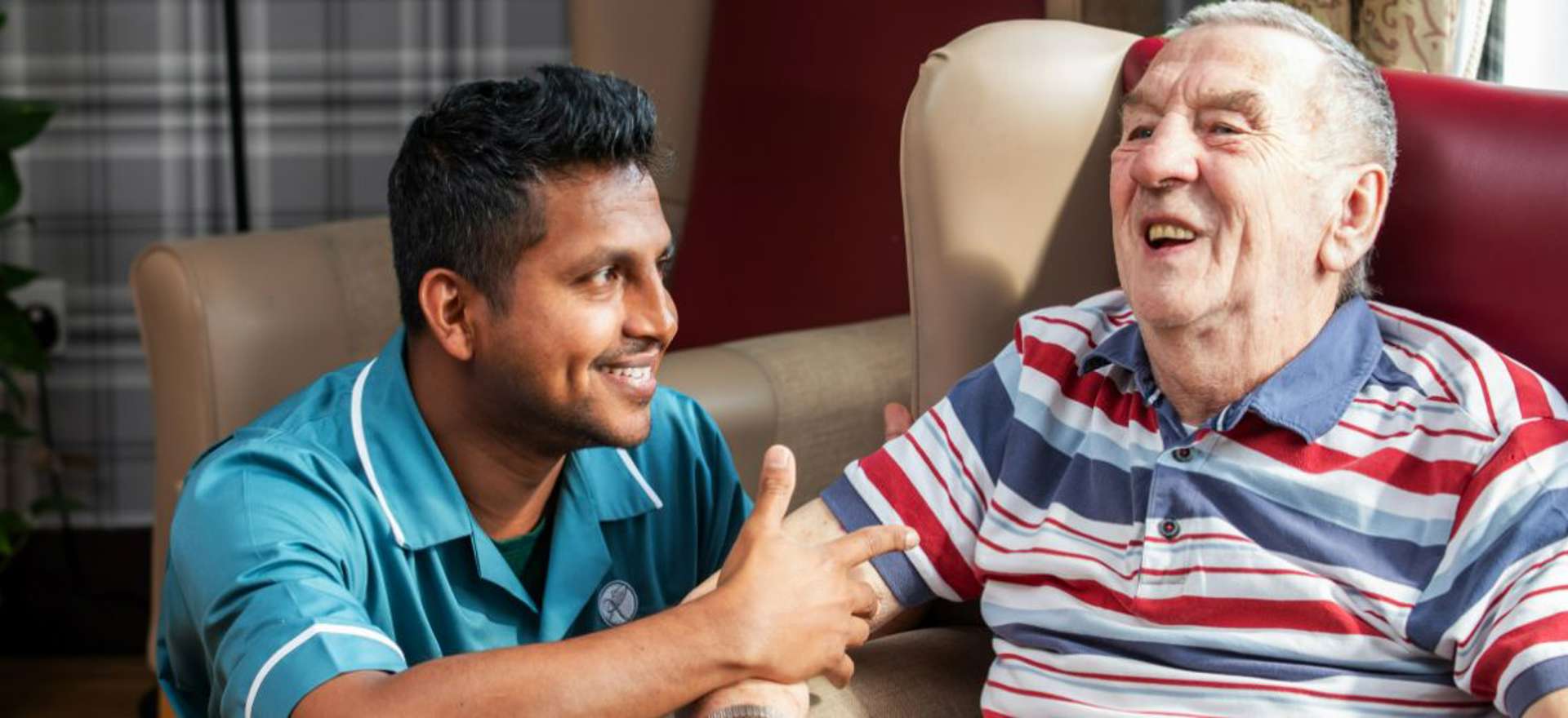 A staff member and resident interact within the homes communal lounge