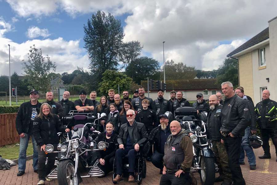 Care home resident Edwin surrounded by local bikers and motorcycles as he prepares for a thrilling biking adventure.