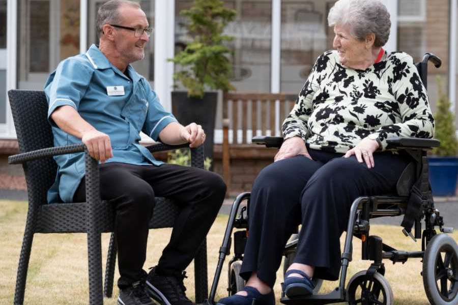 a staff member and a resident sitting in the garden having a chat