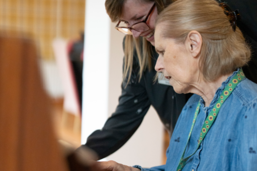 A staff member supports a care home resident to play piano