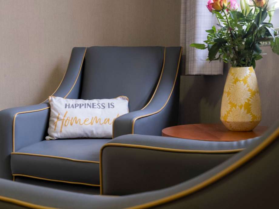 fresh flowers and two grey chairs next to a window within the home