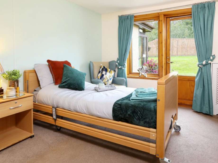 A care home resident's bedroom with furniture and personal touches.