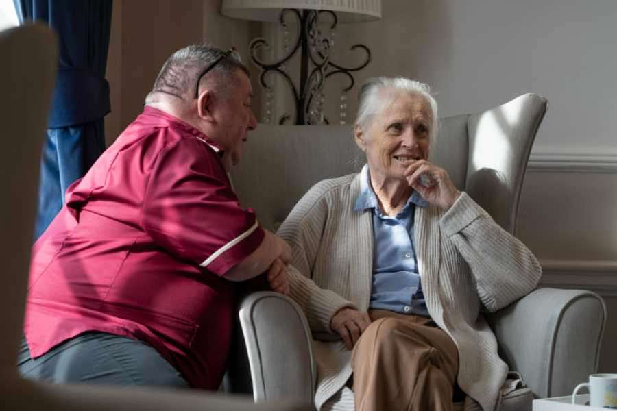 Staff member engages in conversation with a resident in a comfortable lounge setting