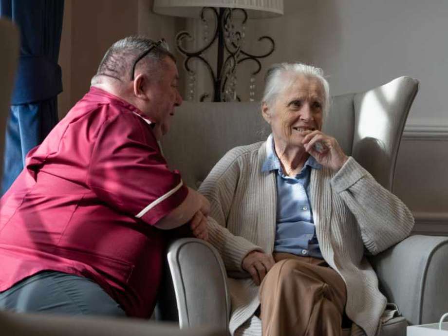 Staff member engages in conversation with a resident in a comfortable lounge setting