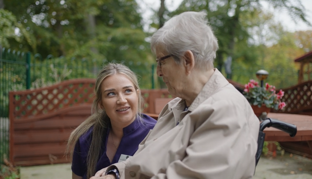 A staff member converses with a resident in the garden 