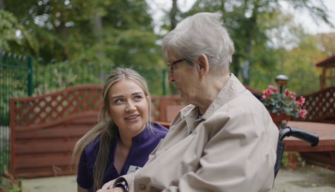 A staff member converses with a resident in the garden