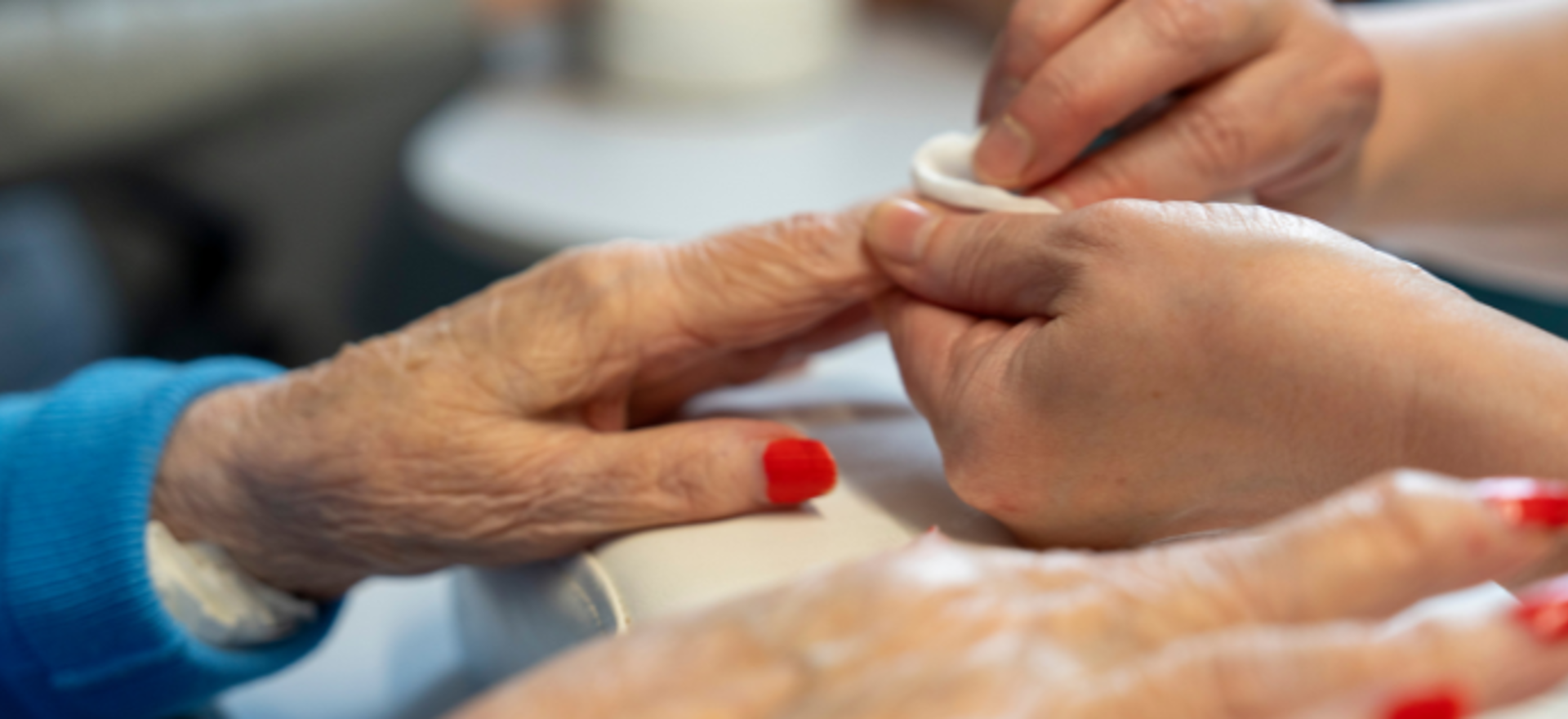 Staff member gently removes nail polish, treating a resident to a relaxing pampering experience