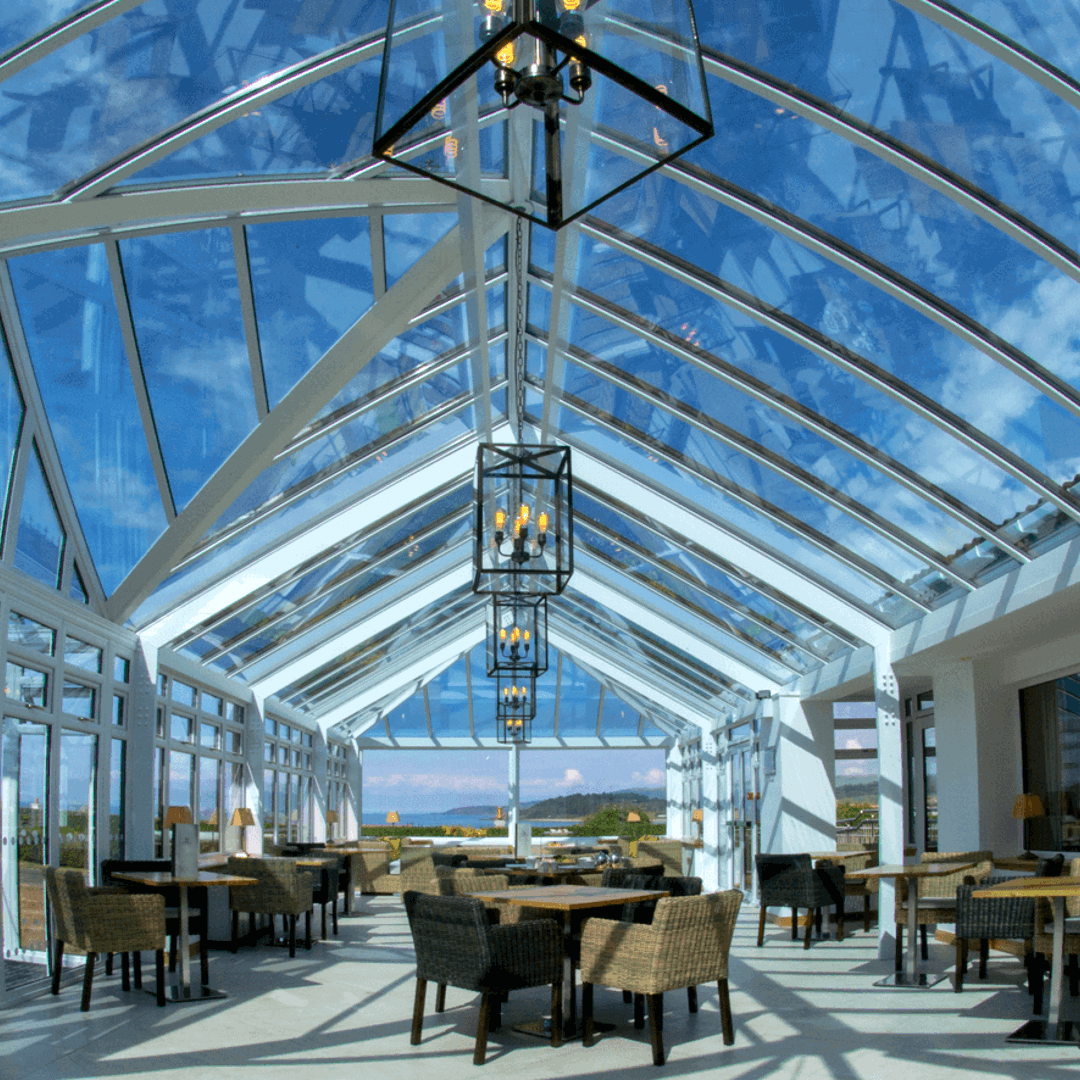 A bright, welcoming conservatory space with wicker seats and wooden tables throughout for dining