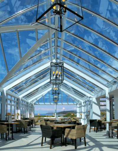 A bright, welcoming conservatory space with wicker seats and wooden tables throughout for dining