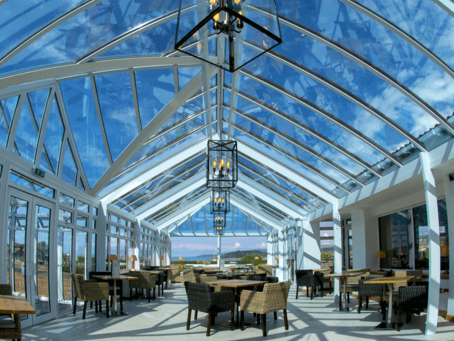 A bright, welcoming conservatory space with wicker seats and wooden tables throughout for dining