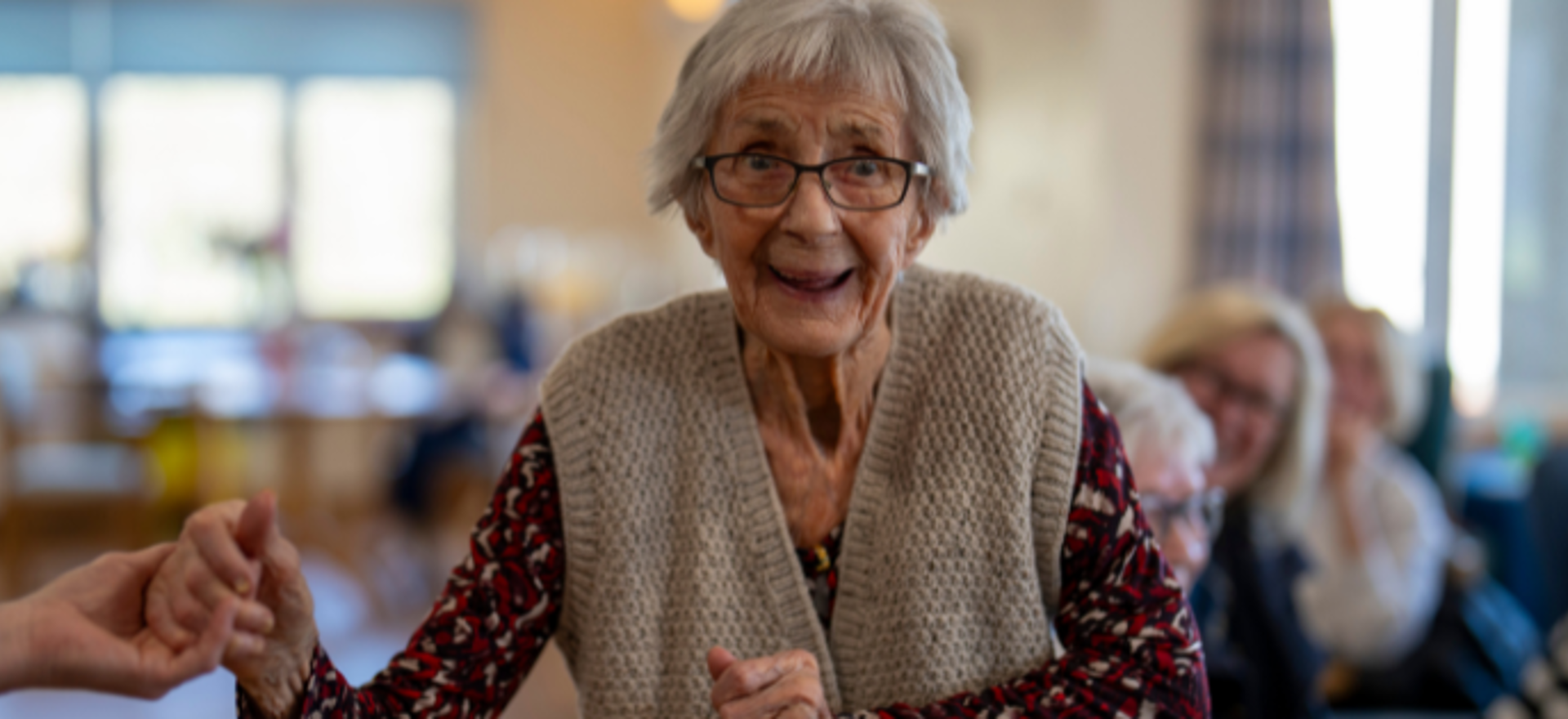 A woman smiles as she dances in a communal lounge