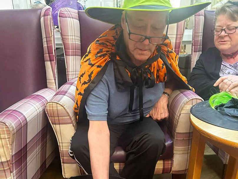 A care home resident engages in an adapted version of dooking for apples this halloween 