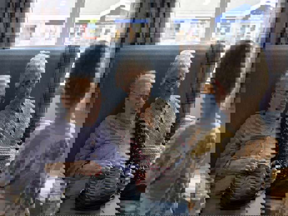 Two care home residents share a warm smile with a visiting nursery child