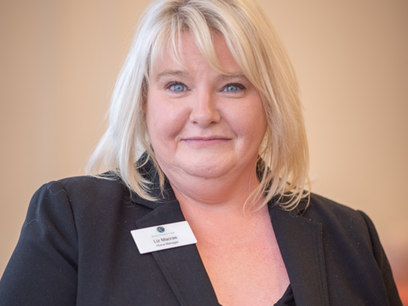 Headshot of care home manager, Liz Macrae. She has blonde hair, and is wearing a black blouse and blazer